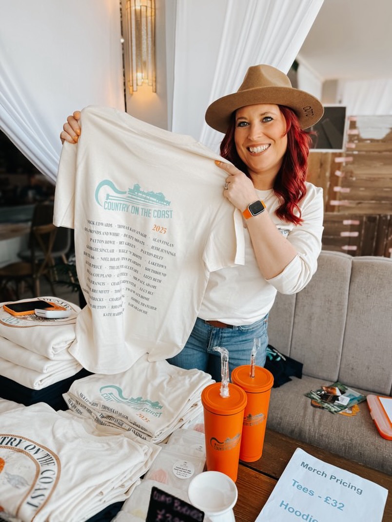 Hannah on the Festival merch table in 2025