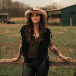 shelly fairchild leaning on a fence
