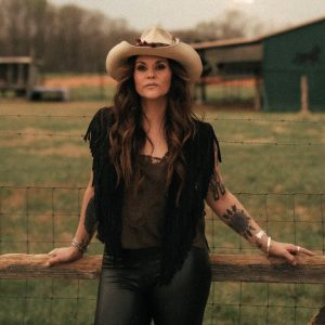 shelly fairchild leaning on a fence